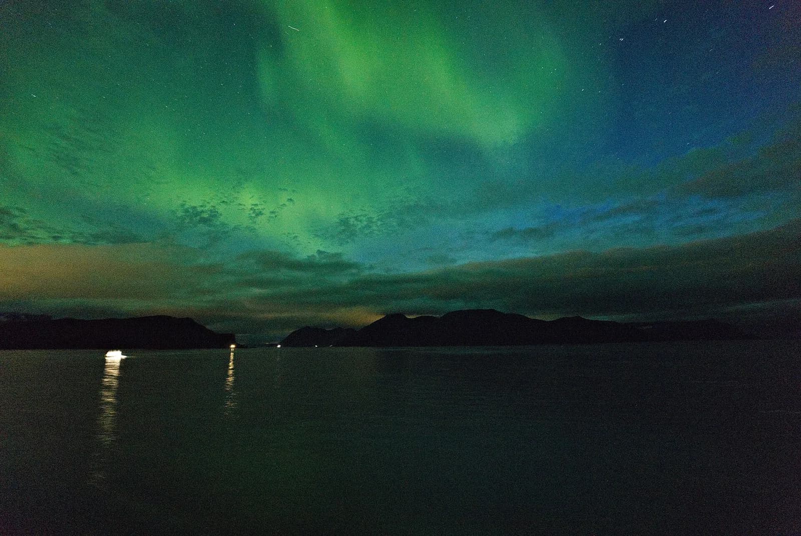 Aurore boréale au-dessus de la mer et de la côte, vue depuis un navire Hurtigruten près de Skjervøy