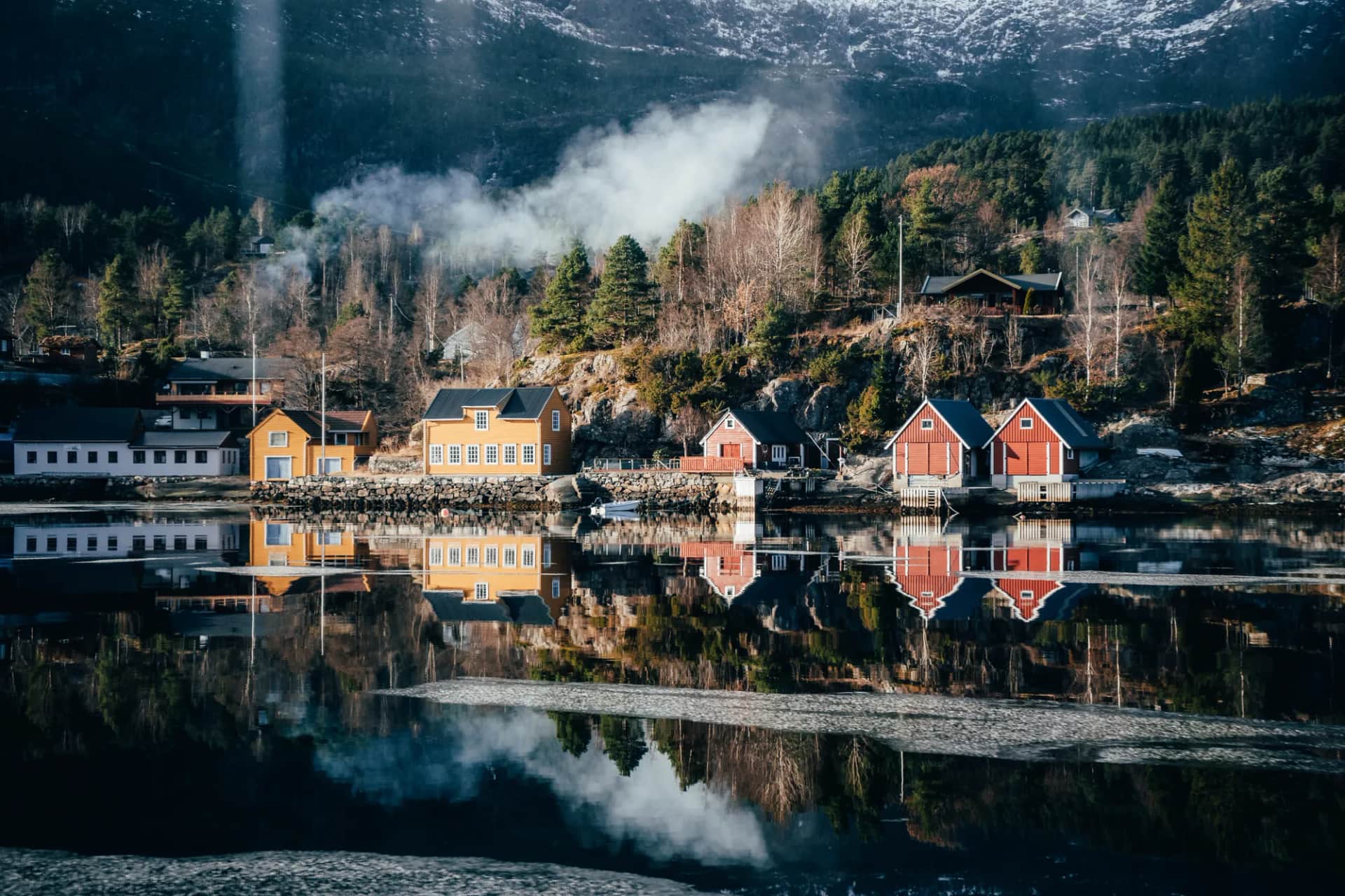 village de maisons colorées se reflétant dans l’Osterfjord, sous des montagnes enneigées, en mars