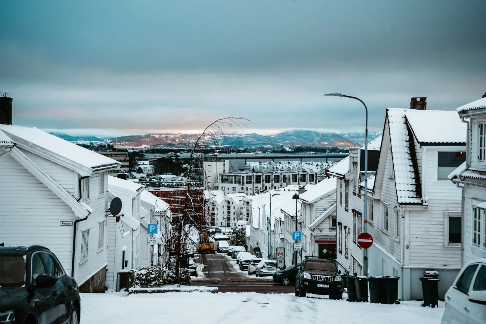 Rue enneigée bordée de maisons blanches à Stavanger, avec vue sur le fjord, le 8 décembre 2022