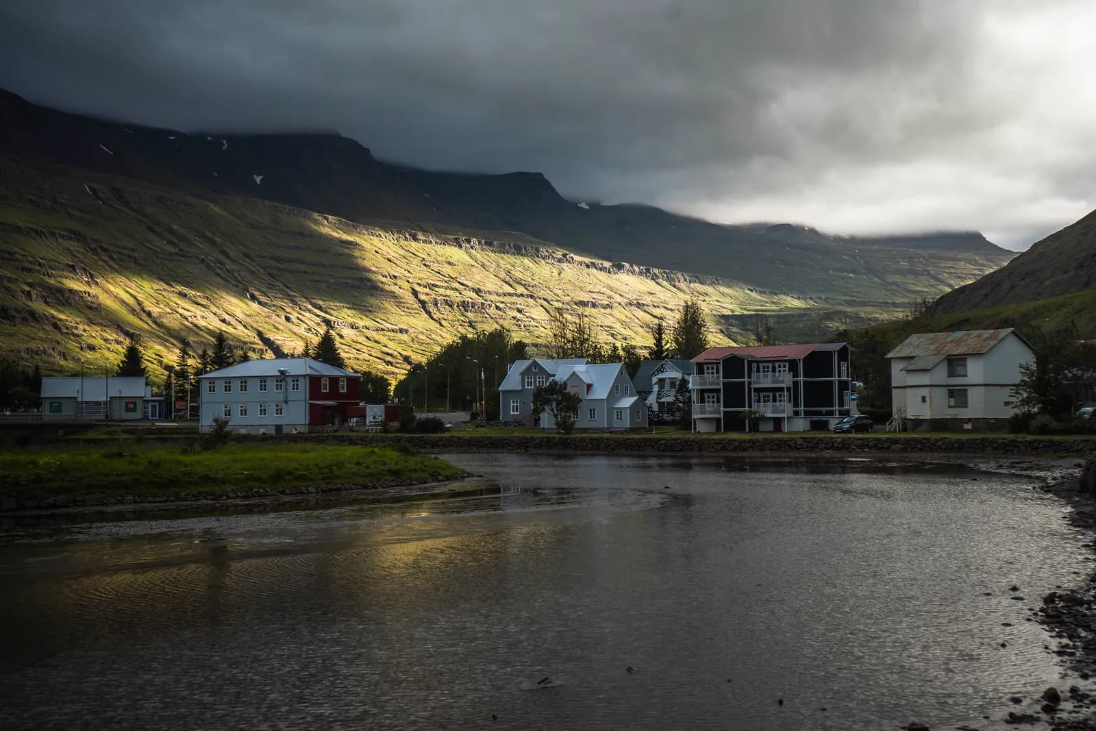 Maisons au bord d'un fjord islandais sous un ciel d'orage, en juillet 2023