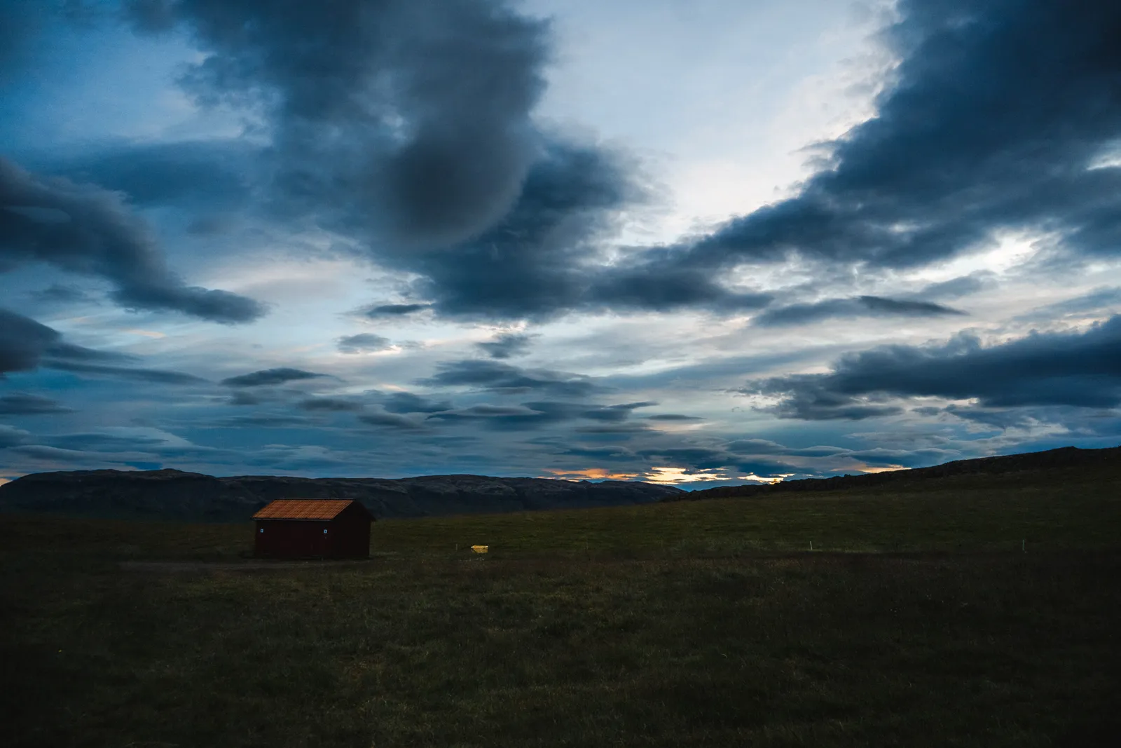 cabane rouge dans la plaine sous un ciel encore clair, vers 2 heures du matin en juillet