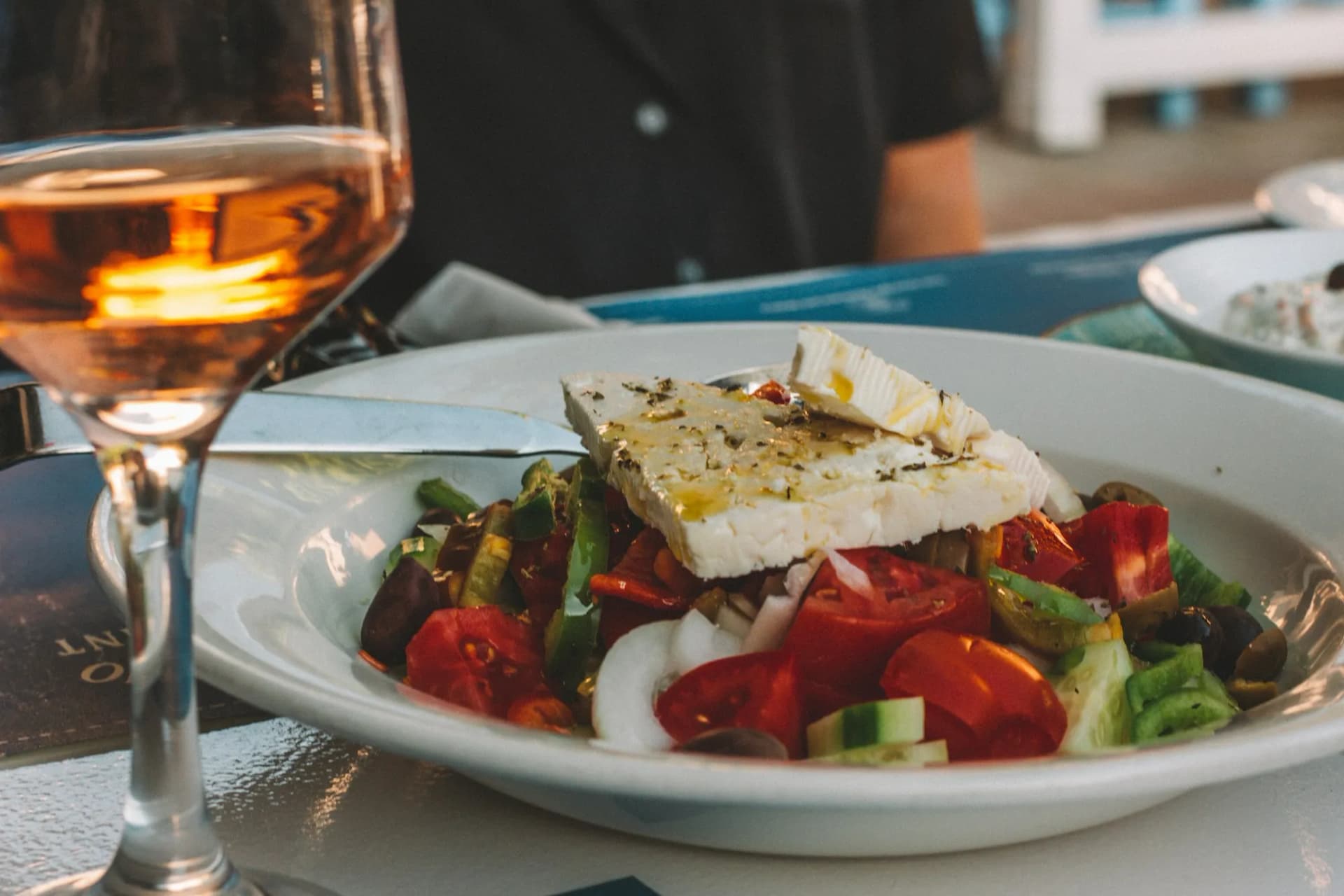 Greek salad and a glass of wine on a terrace