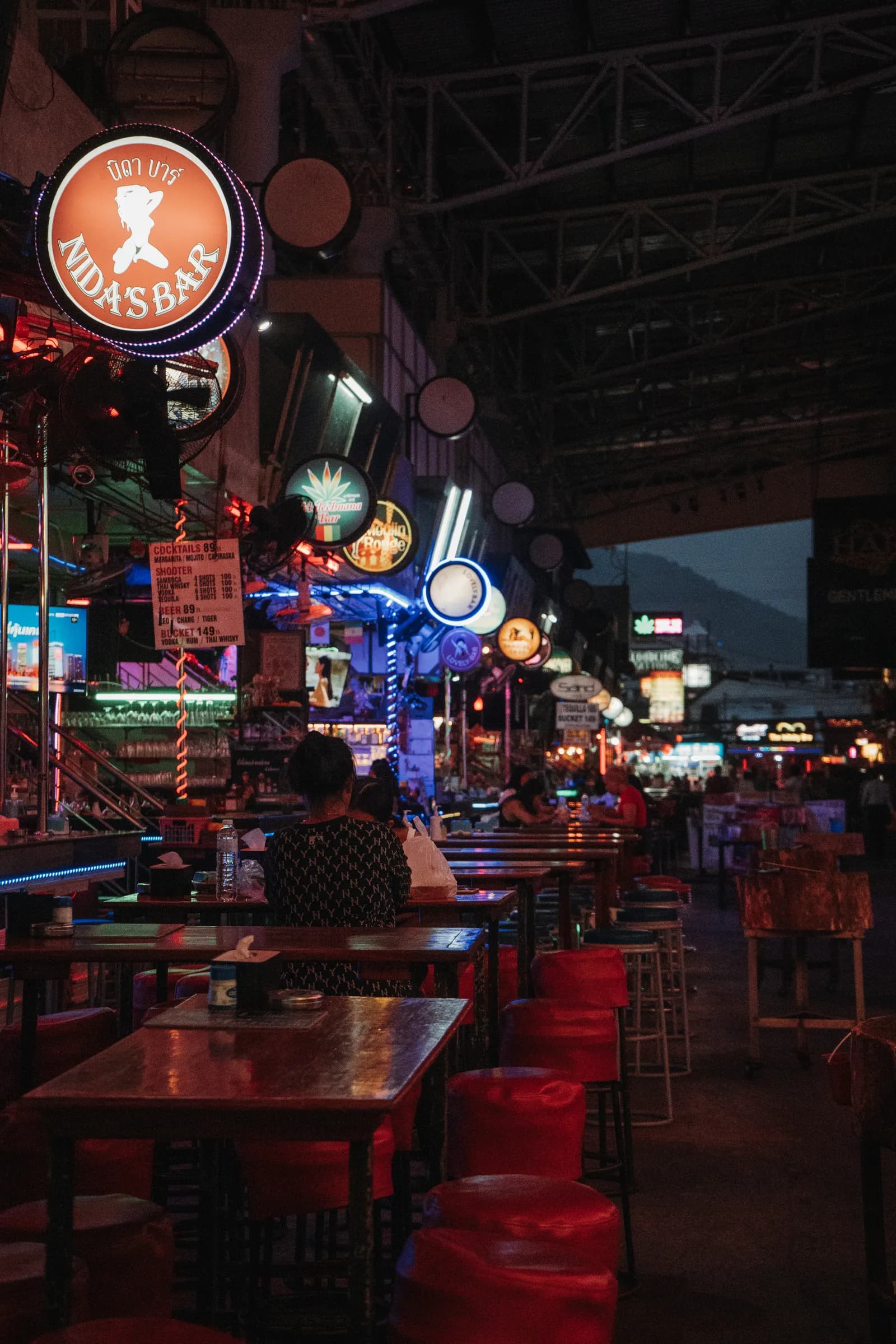 Enseignes lumineuses et tabourets rouges d'un bar en plein air de Bangla Road, encore presque vide en début de soirée
