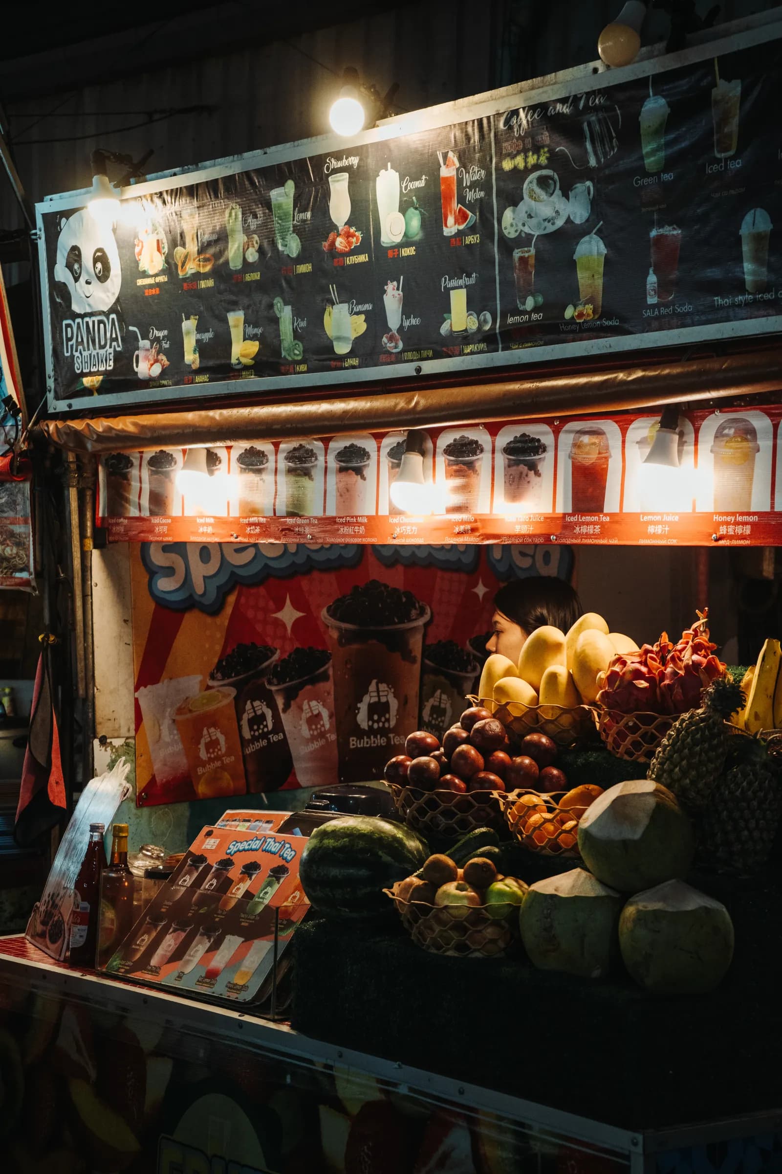 Étal de fruits frais, noix de coco et smoothies éclairé de nuit au marché street food de Patong