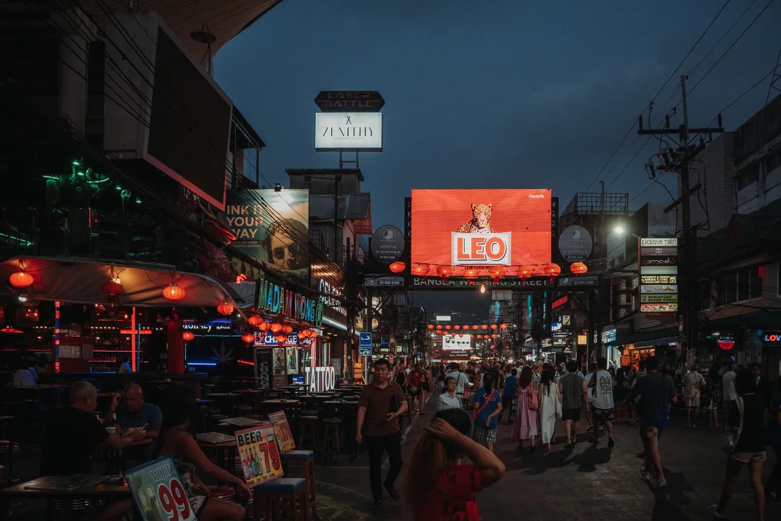 Bangla Road à la nuit tombante, panneau publicitaire géant, lanternes rouges et terrasses de bars au néon