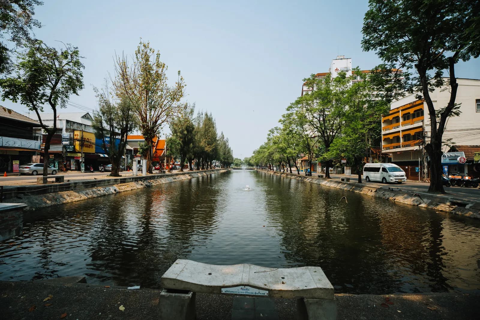 Douves et avenue arborée de Chiang Mai sous un ciel pâle, fin mars