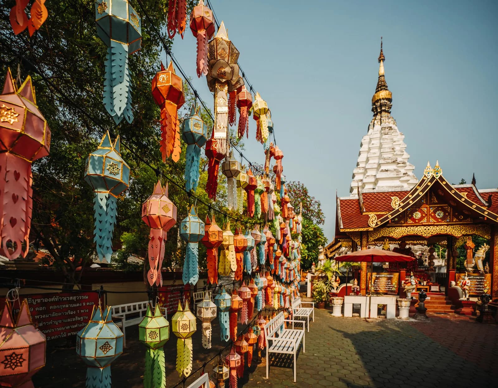 Mur de lanternes lanna colorées devant un chedi blanc dans un temple de la vieille ville de Chiang Mai