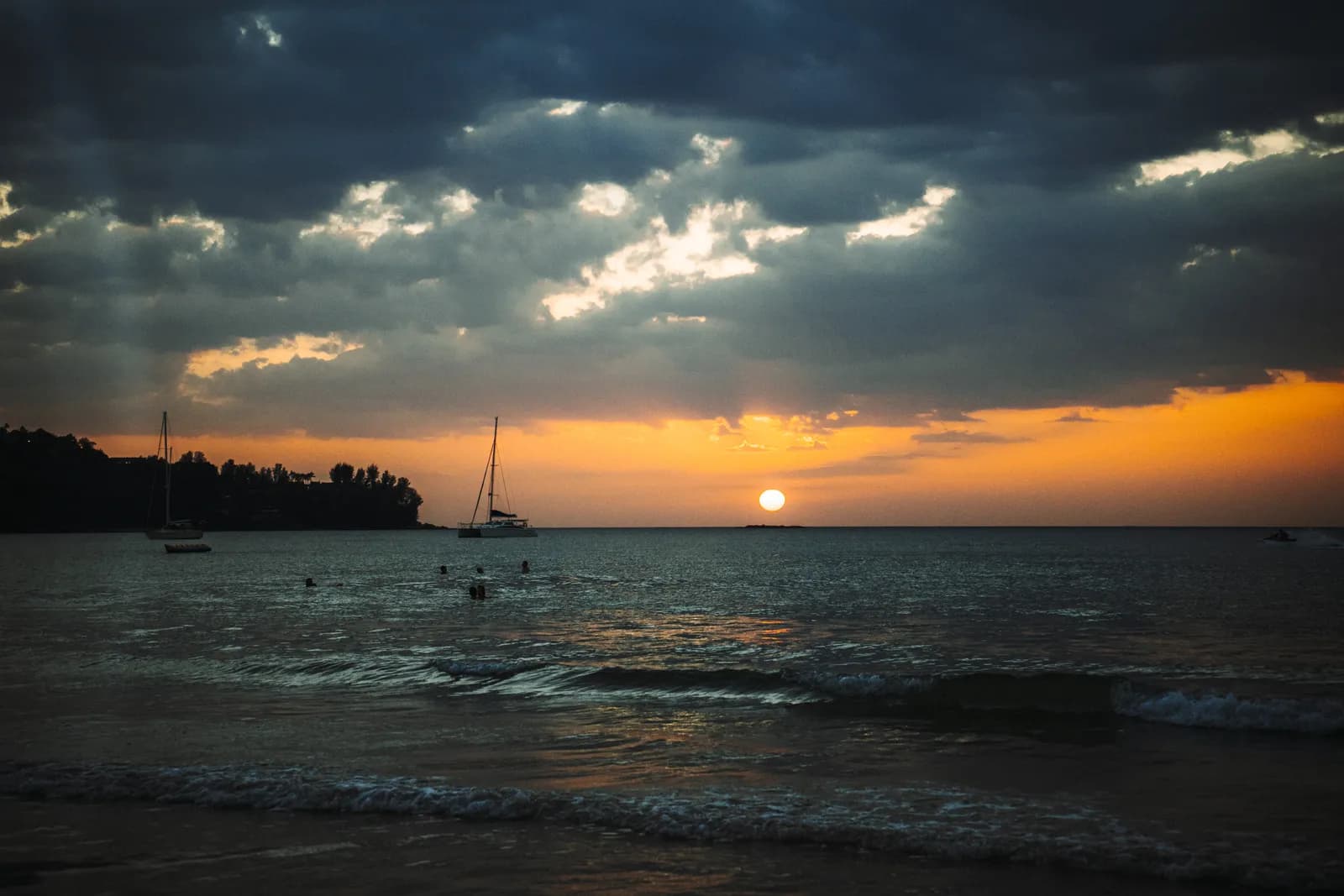 Coucher de soleil orange sur la baie de Kamala, à Phuket, avec deux voiliers au mouillage