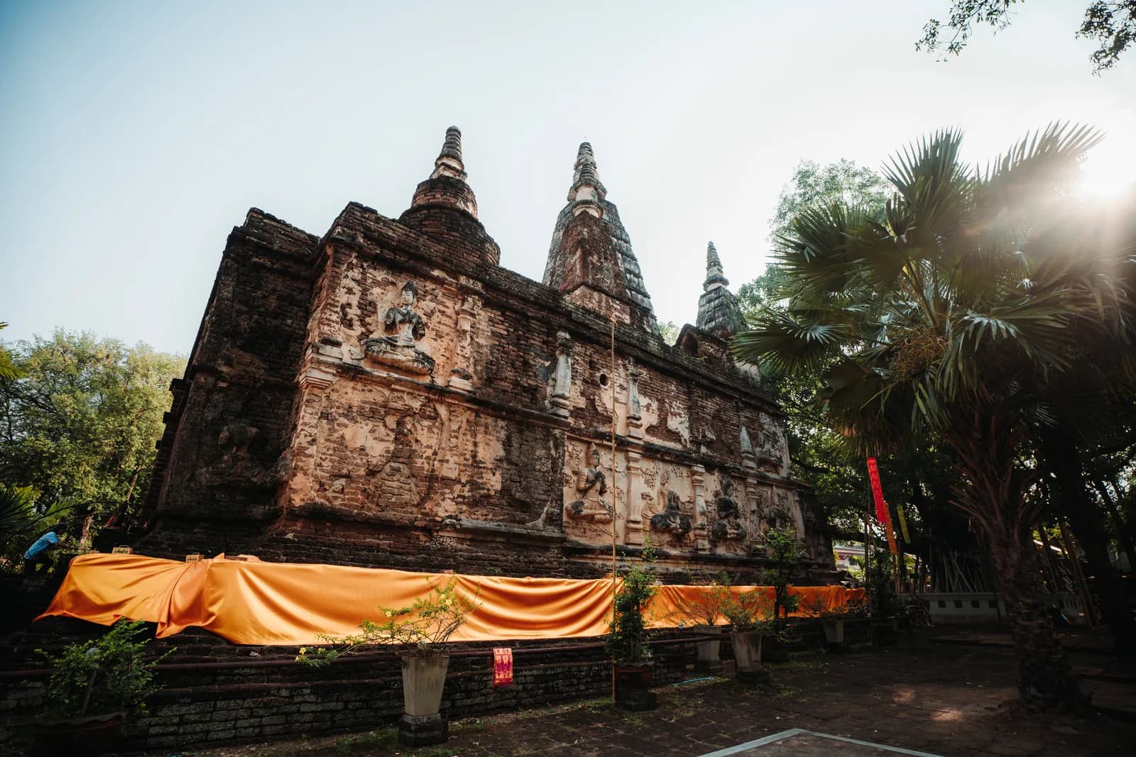 Flanc du vihan de Wat Chet Yot orné de divinités en stuc, drapé d'étoffe orange, dans la lumière basse