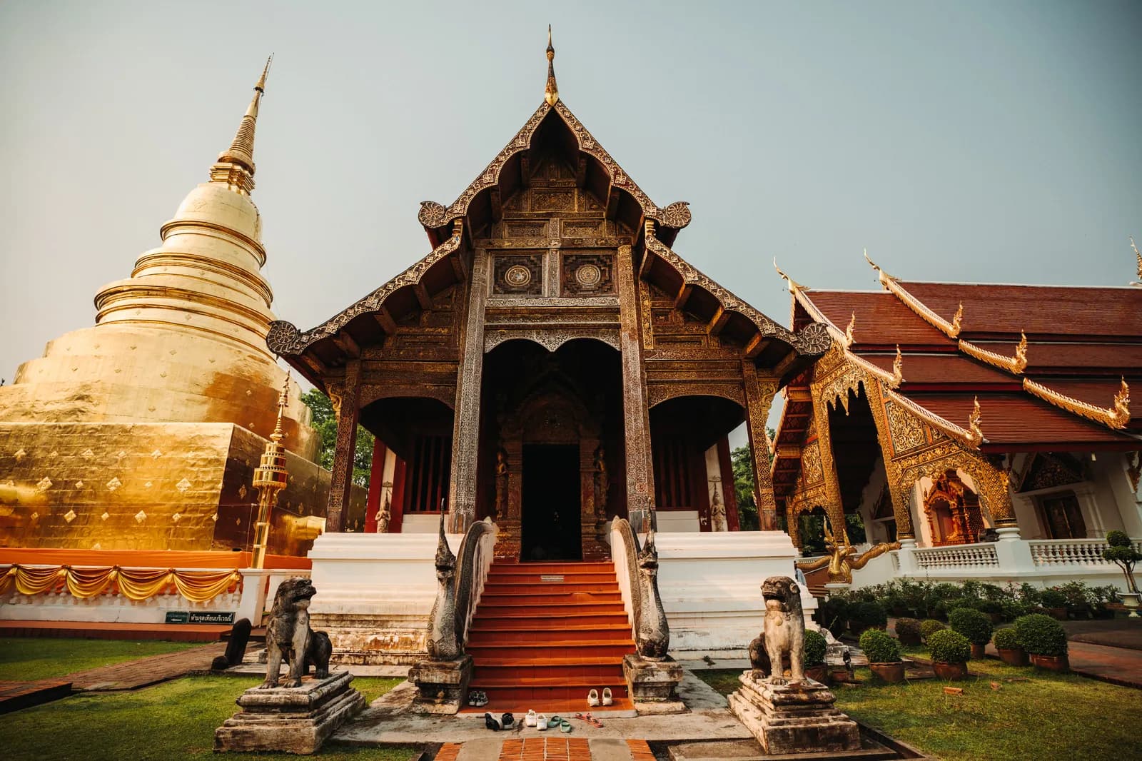 Viharn Lai Kham en bois sculpté et chedi doré de Wat Phra Singh, gardés par deux lions, à Chiang Mai