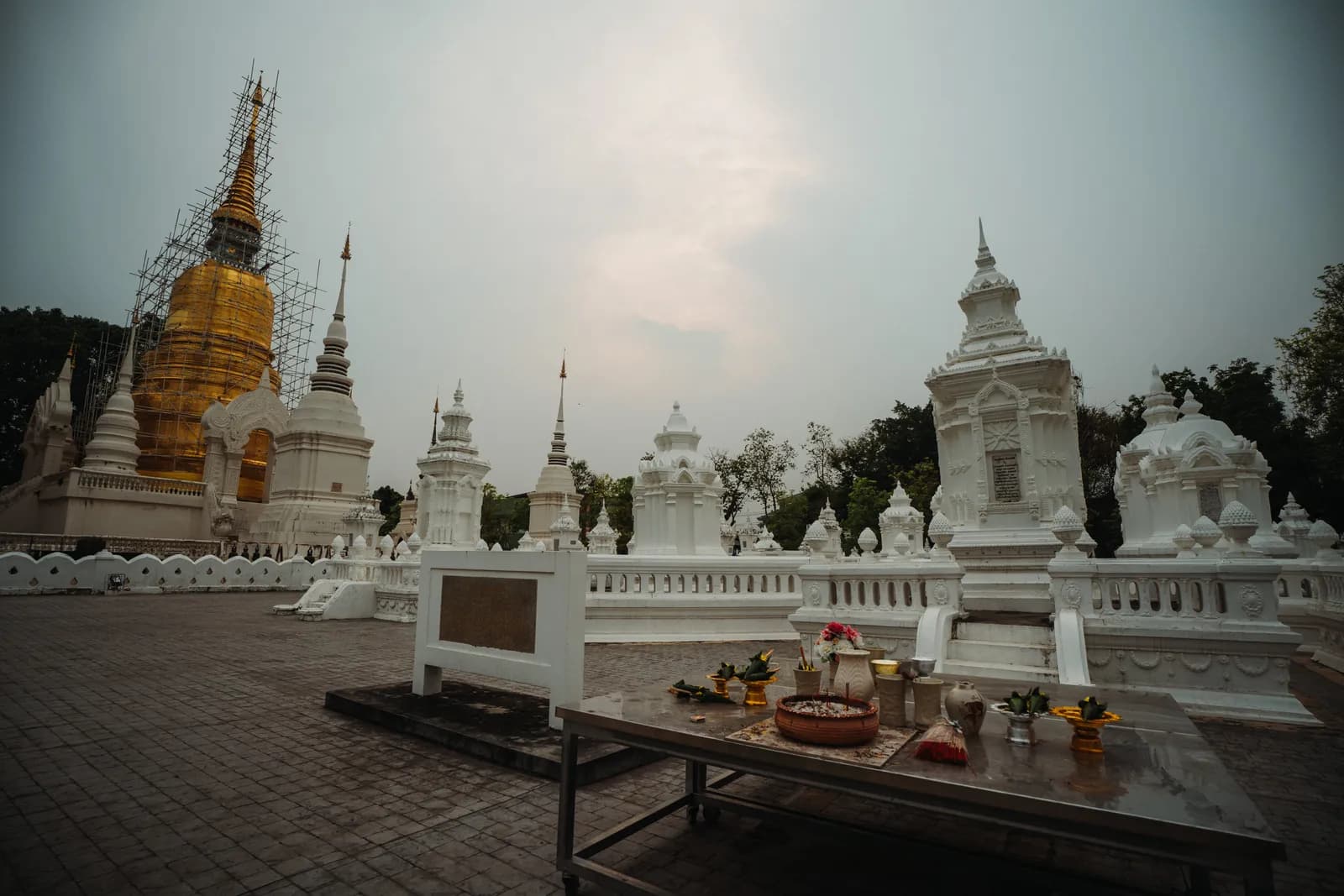 Champ de chedis blancs des princes de Chiang Mai devant le grand chedi doré sous échafaudage de Wat Suan Dok