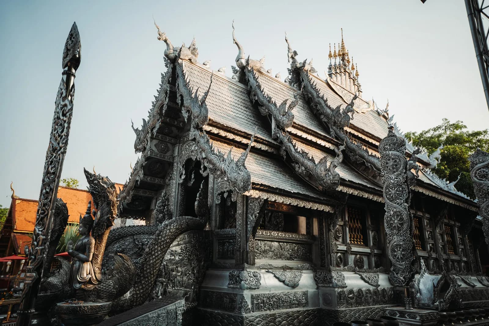 Toits étagés et nagas entièrement ciselés dans le métal argenté de l'ubosot de Wat Sri Suphan, à Chiang Mai