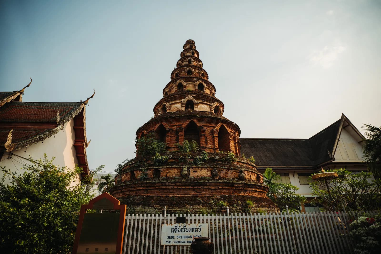 Chedi rond à sept gradins et niches de Wat Phuak Hong derrière sa clôture blanche, à Chiang Mai