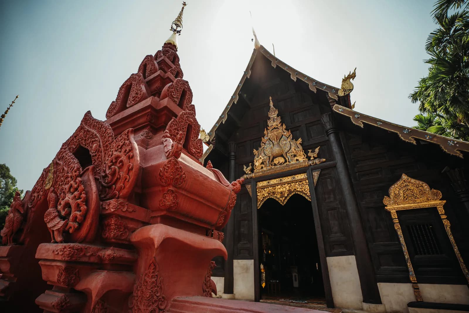 Porche en stuc rouge sculpté et vihan en teck sombre de Wat Phan Tao, voisin de Wat Chedi Luang