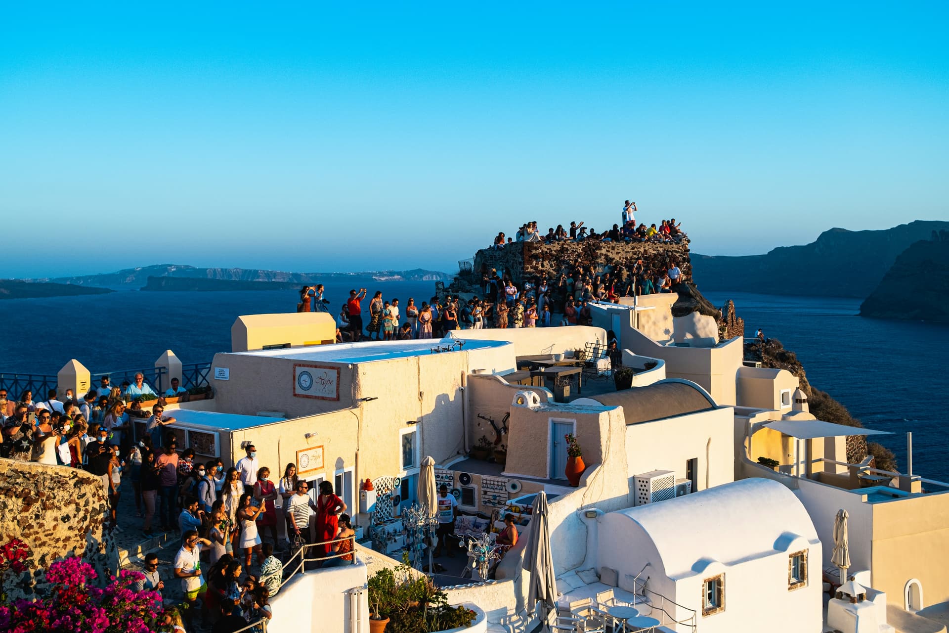 Panoramic view from Oia Castle at sunset with windmills