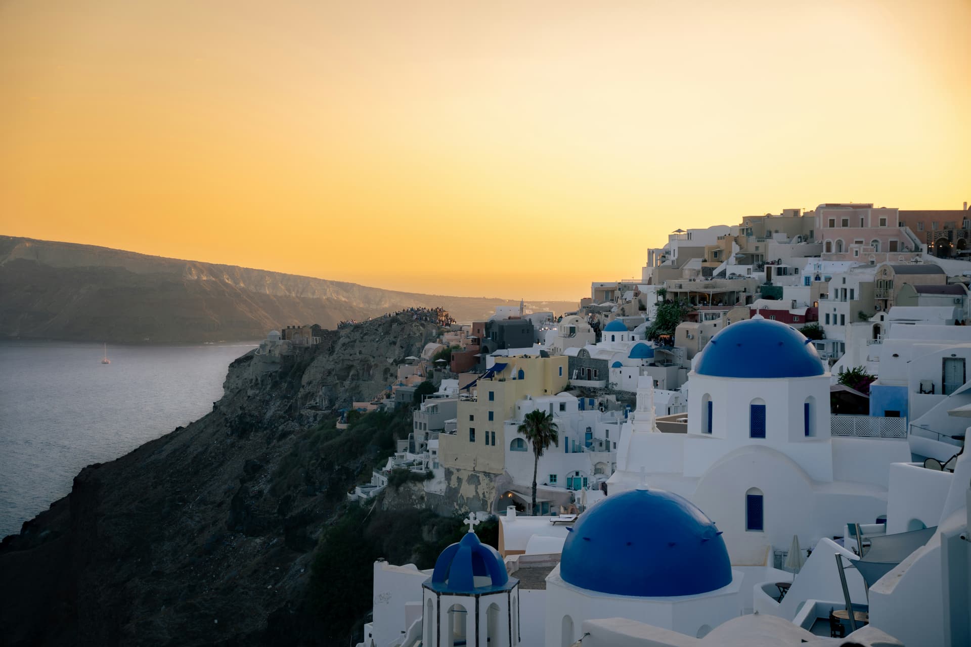 The three blue domes of Oia bathed in golden sunset light
