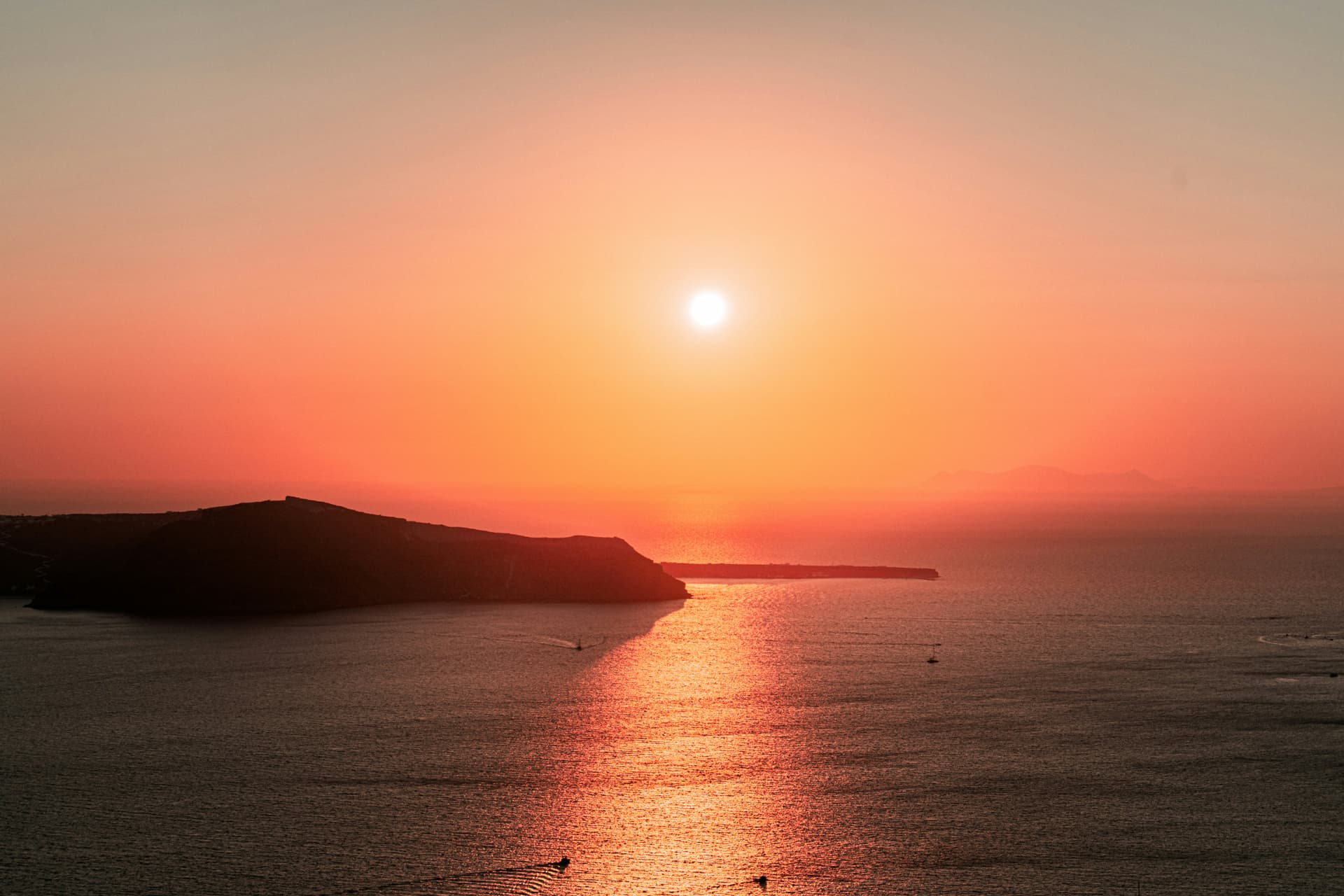View from a catamaran of Oia lit up by the sunset