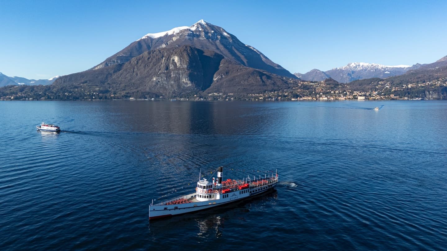 Passenger ferry cruising on the calm waters of Lake Como with mountains in the background