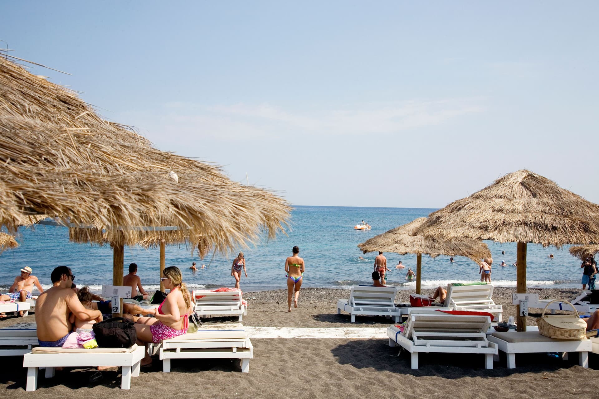 Plage de Perivolos à Santorin avec sable noir, transats colorés et mer turquoise
