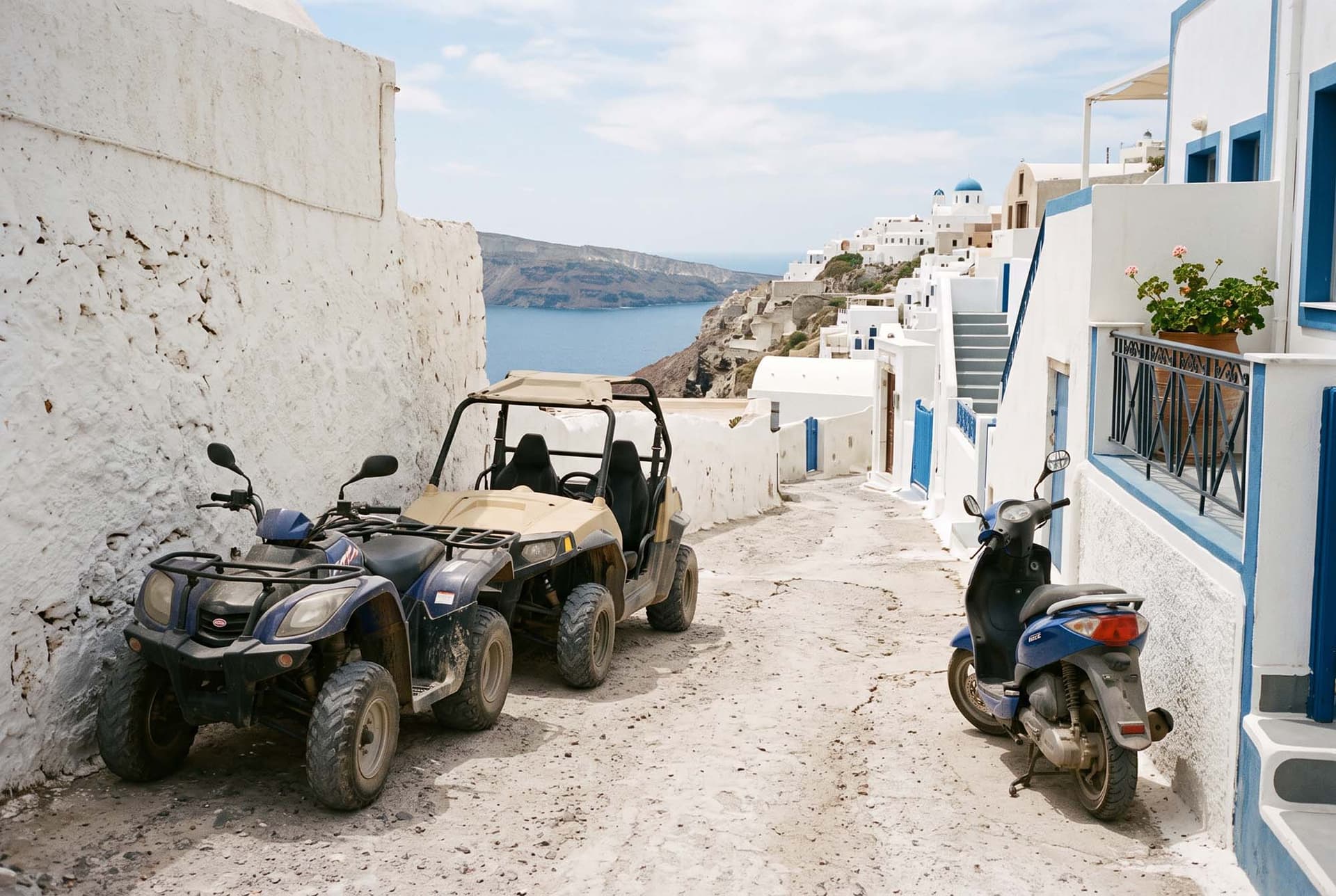 A quad, a buggy and a scooter parked in a white alley of Fira in Santorini