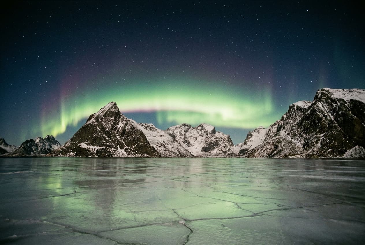 Aurore boréale verte au-dessus des montagnes enneigées près de Tromsø en Norvège