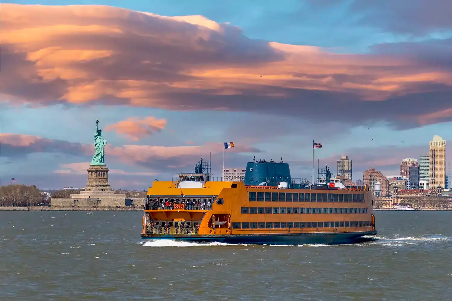 Ferry de Staten Island venant de Manhattan et passant par la Statue de la Liberté. La Statue de la Liberté et les gratte-ciel du bas de Manhattan sont visibles en arrière-plan.